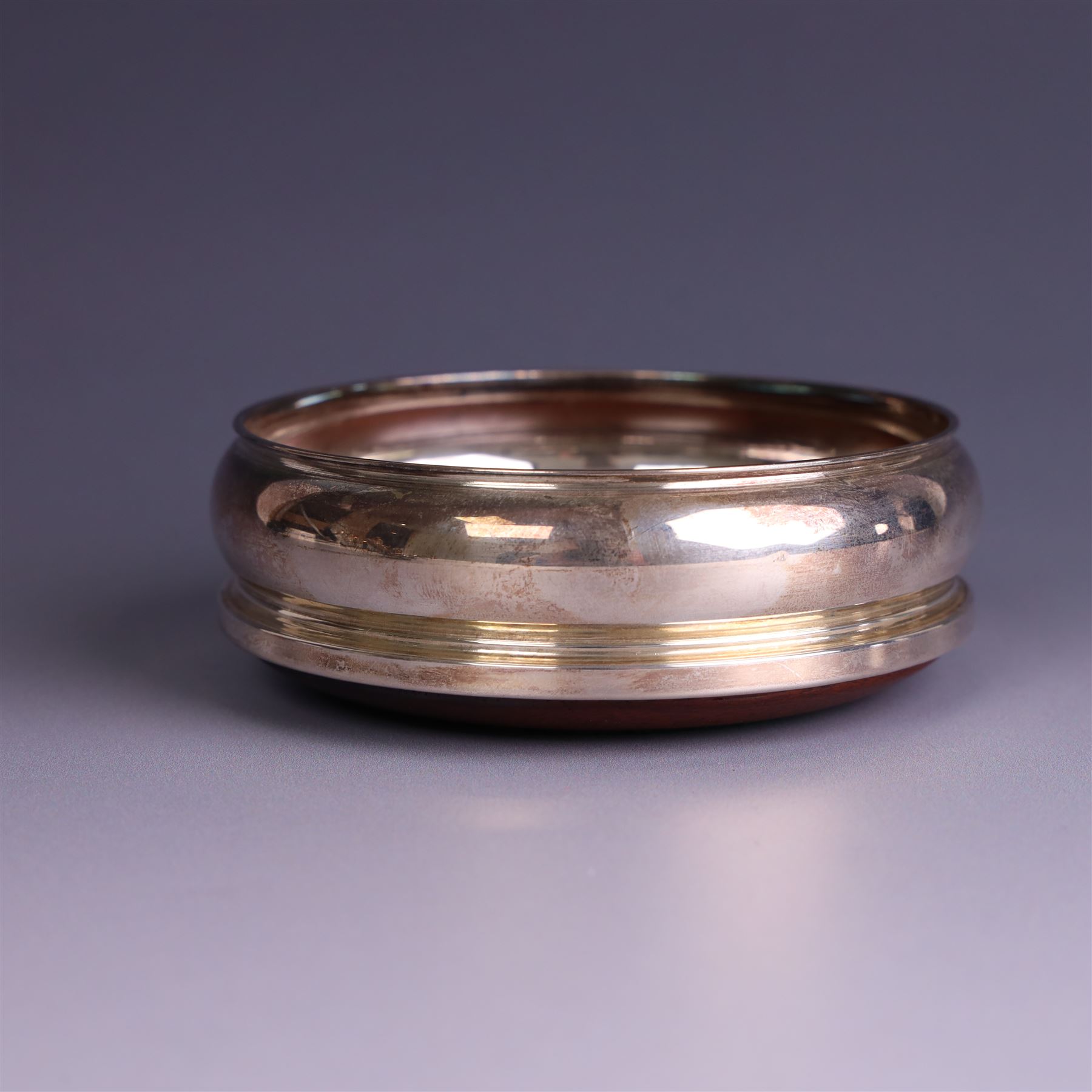 Modern silver mounted bottle coaster, with turned wooden base, hallmarked Carrs of Sheffield Ltd, Sheffield 2003 and a Victorian silver inkwell stand, hallmarks worn and indistinct, coaster D10cm