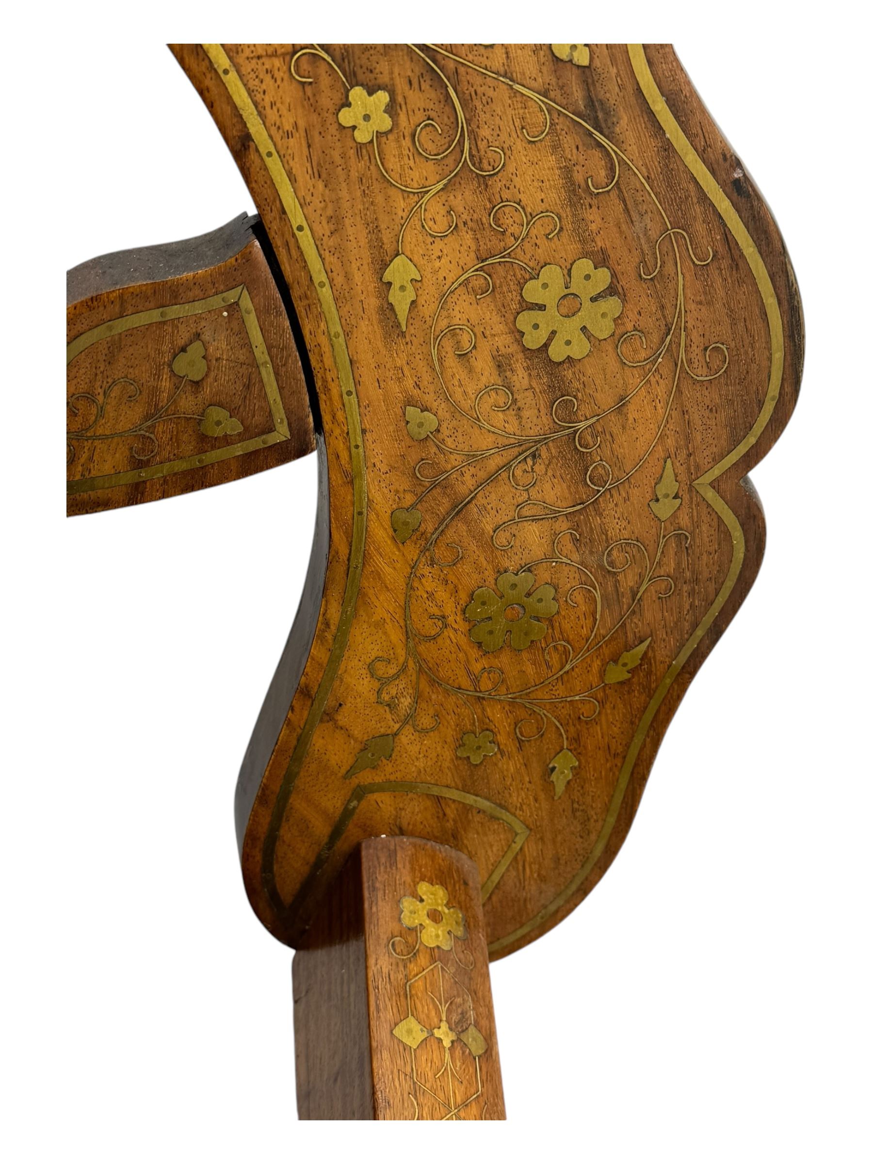 Late 20th century brass inlaid hardwood throne chair, curved X-frame form, raised shaped back inlaid with trailing leafy branches and flower heads, on sledge feet 