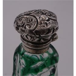 Late Victorian green flashed and facet cut scent bottle, of pear shaped form with hinged foliate detailed silver cover, opening to reveal an interior glass stopper, H8cm, unmarked but testing as silver, together with a further late Victorian clear cut glass example, of cylindrical form, also with hinged foliate detailed silver cover, opening to reveal and interior glass stopper, hallmarked M Bros, Birmingham 1899, H7cm, (2)