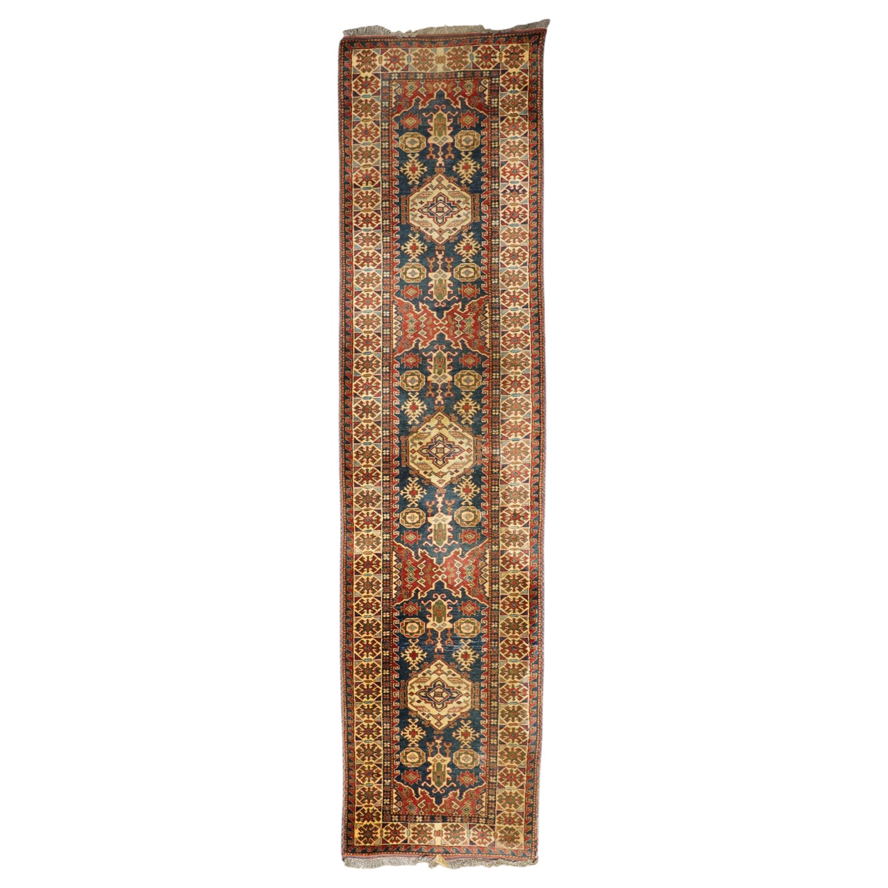Caucasian hand-knotted runner, dark navy ground with three ivory geometric medallions surrounded by stylised flowerheads and angular motifs in madder red, green and ivory, enclosed by repeating geometric borders