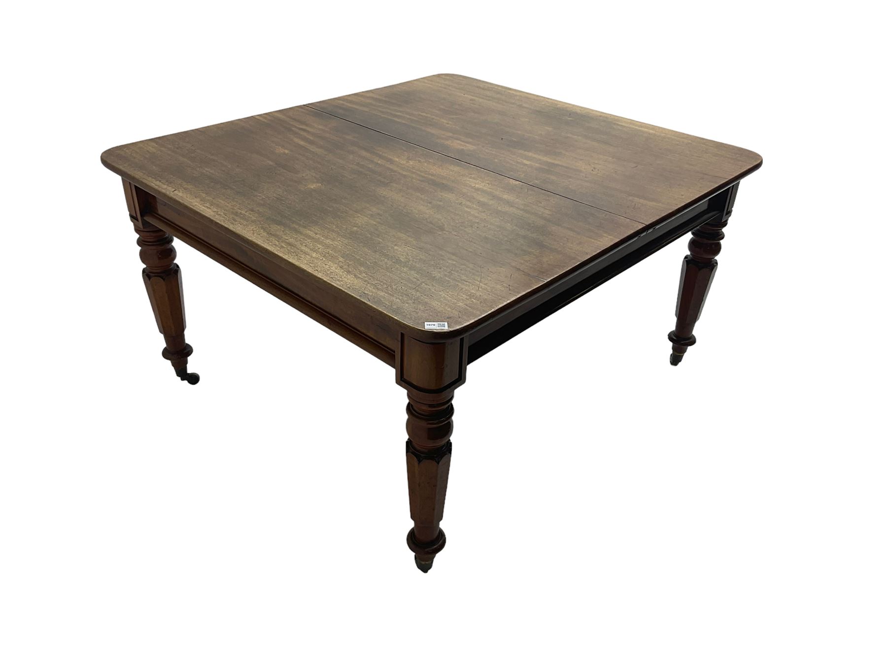 Late 19th century extending mahogany dining table, square top with banded frieze rail, raised on turned octagonal supports with  brass cups and castors, with two additional leaves