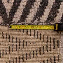 Moroccan Berber hand-knotted rug, of rectangular form, ivory ground decorated with bold, repeating lozenge motifs defined by alternating charcoal grey linear bands, with a striking geometric lattice and chevron with diamond designs, enclosing smaller stylized devices in soft blush tones, with fringe ends