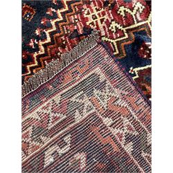 Persian Shiraz rug, red ground field decorated with linked triple lozenge medallions, decorated all over with stylised flower and plant motifs, geometric design triple band border