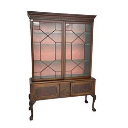 19th century mahogany bookcase display cabinet on stand, dentil cornice over blind fretwork frieze, fitted with two astragal glazed doors enclosing two shelves, above two cupboards with re-entrant panelled facias flanking blind-fretwork panel in stylised plant motif form, raised cabriole supports with ball and claw feet