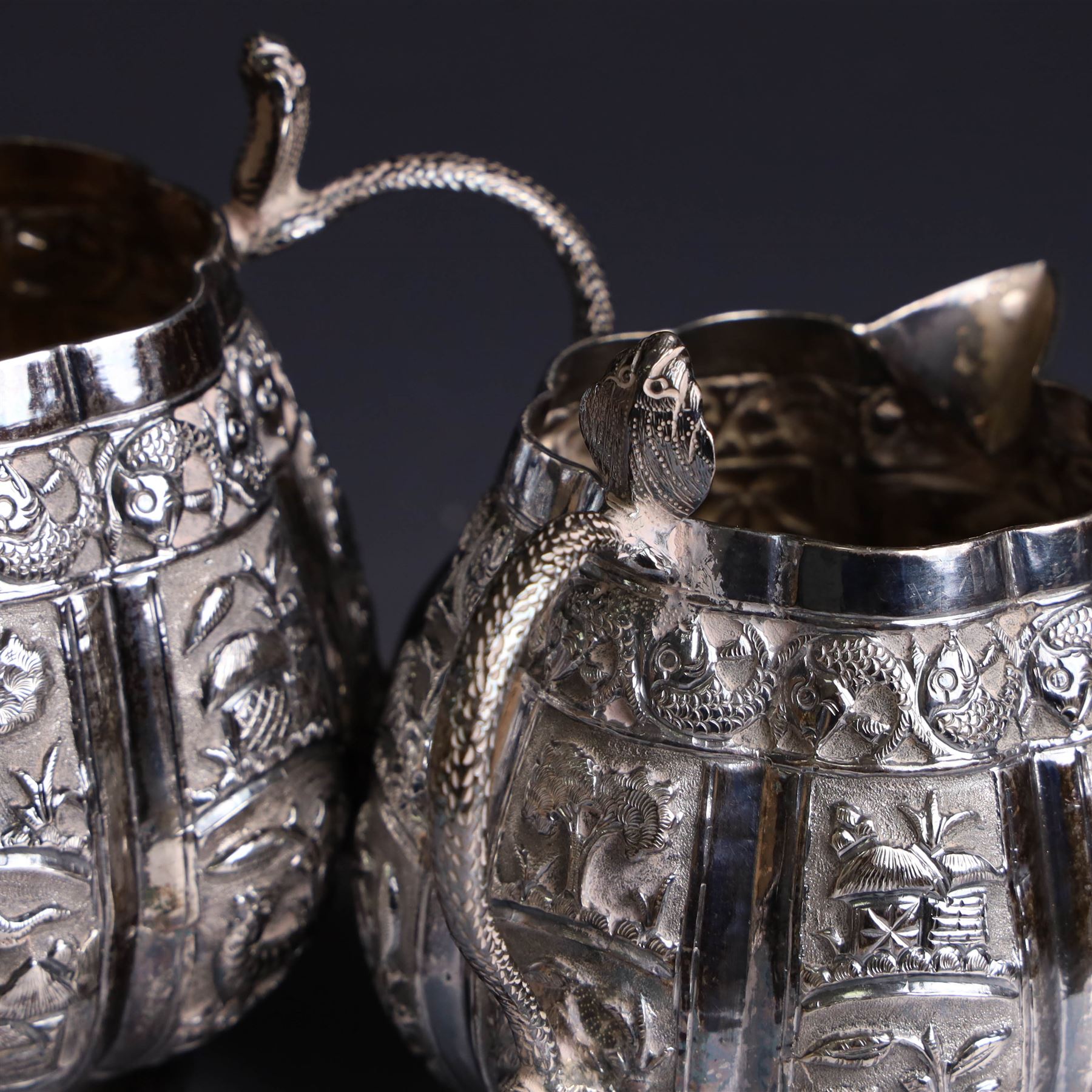 Three piece Indian silver tea service, comprising teapot, twin handled open sucrier and cream jug, each with embossed animal decoration with fish border, serpent handles and elephant finial, teapot H17cm
