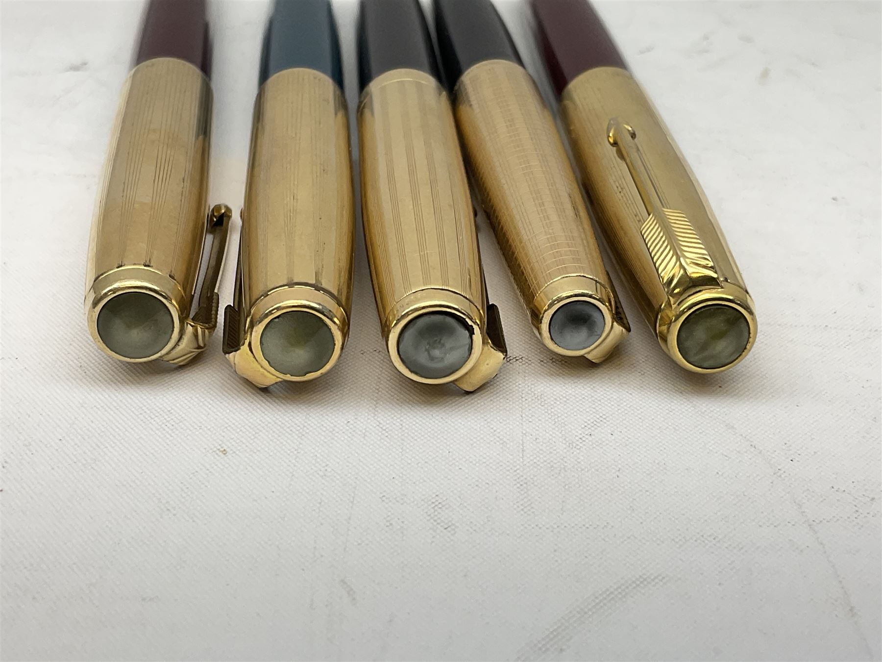 Five Parker fountain pens with gold caps, to include 65 Consort Insignia with rolled cross hatch