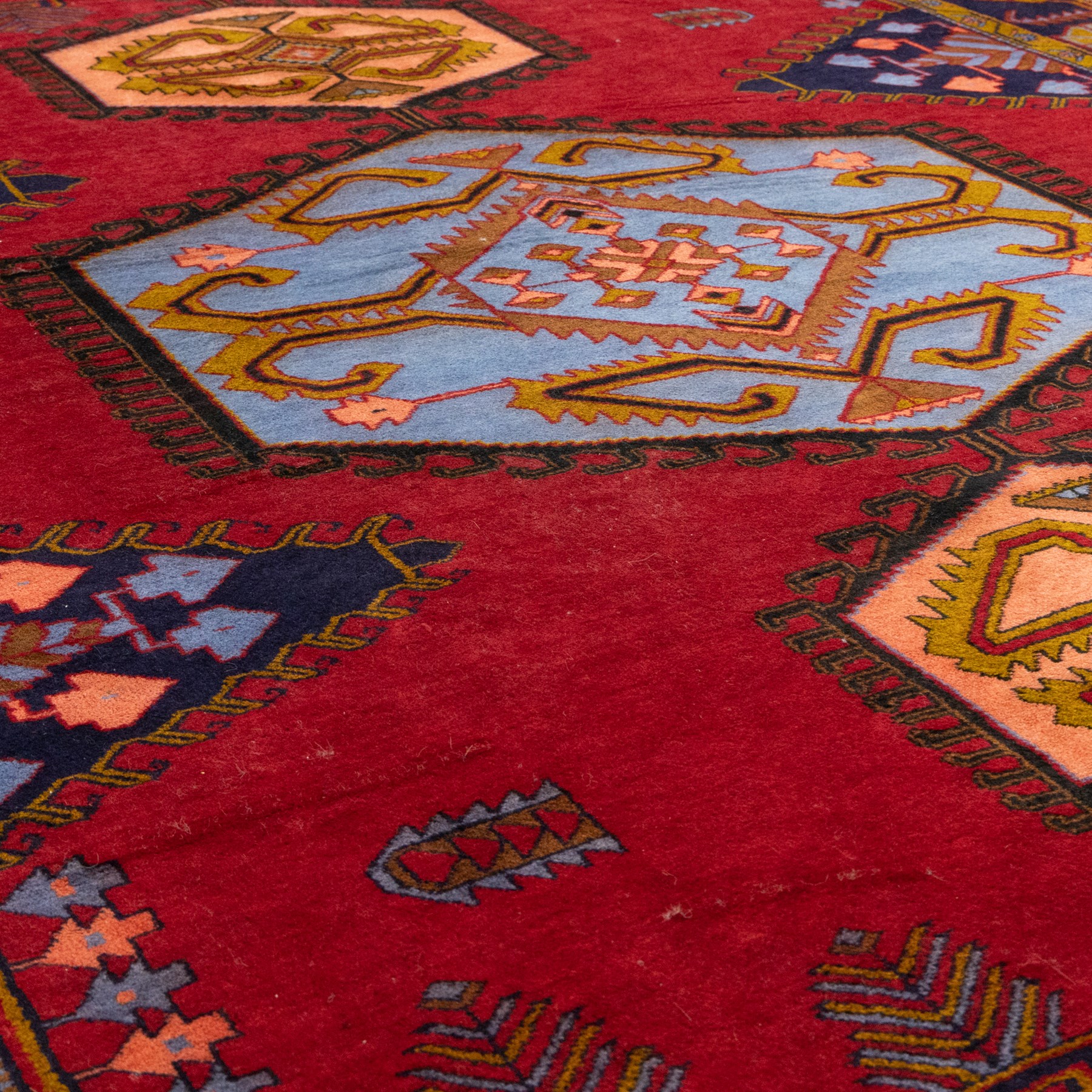 Turkish Anatolian hand-knotted carpet, red field centred by a large pale blue geometric medallion flanked by pink octagonal medallions, scattered stylised motifs, enclosed by multiple geometric borders