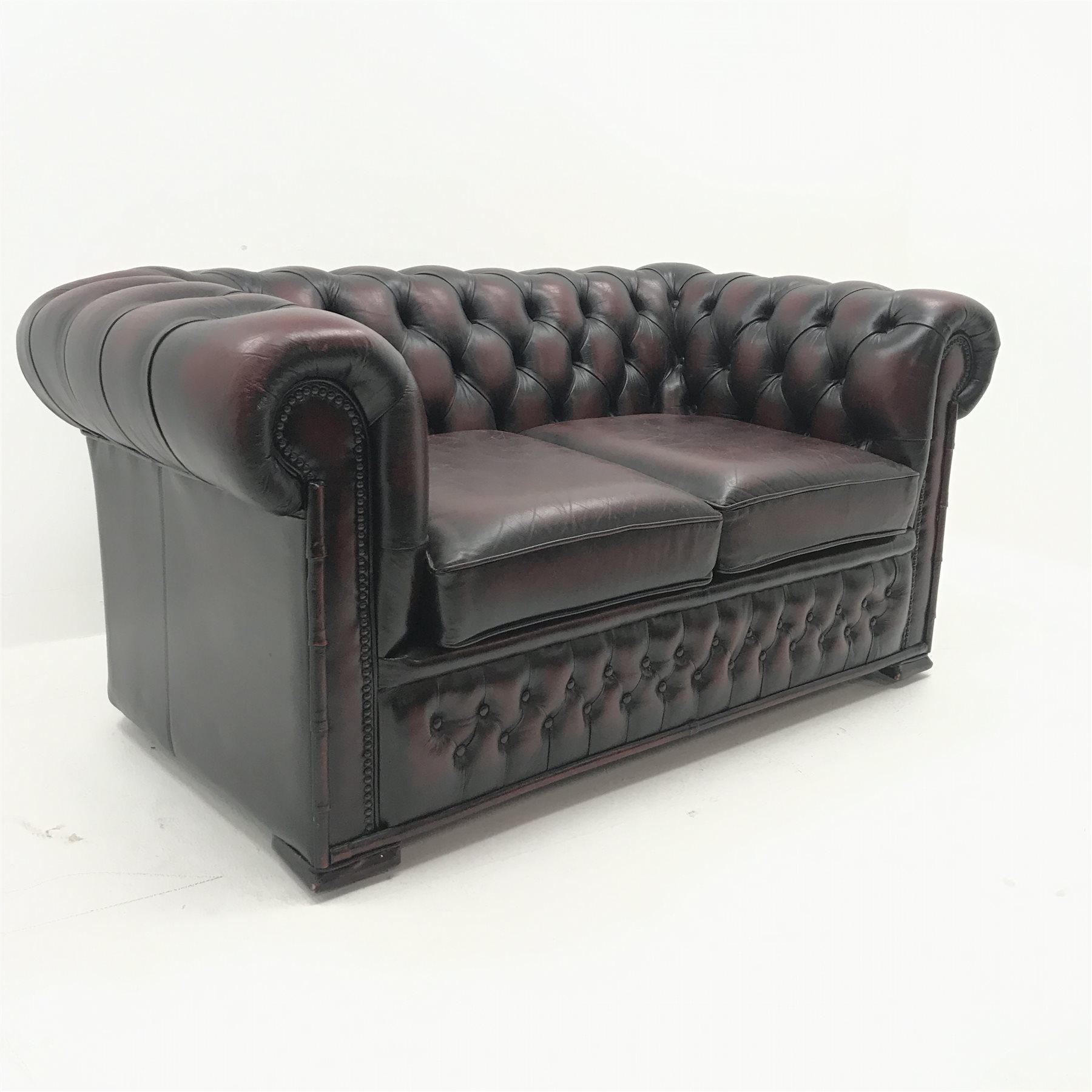 Two seat chesterfield sofa upholstered in deep buttoned ox blood