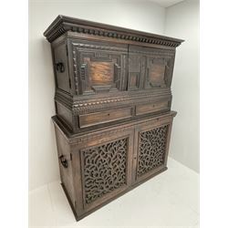 18th century and later carved campaign chest on cupboard, the top section with projecting cornice over two doors with raised geometric mouldings, incised carved decoration throughout, two drawers, fitted with carrying handles, the lower section fitted with slide above cupboard enclosed by two fretwork panelled doors