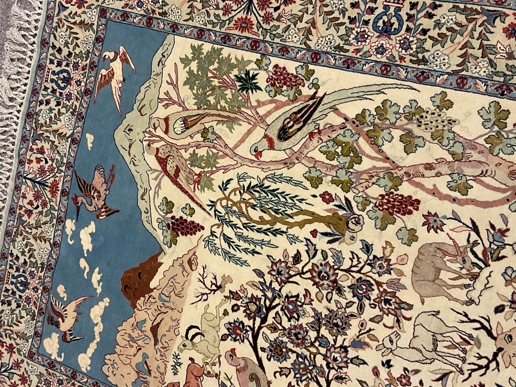 Fine Persian tree of life rug wall hanging, ivory ground field depicting landscape filled with animals, birds and flowers, the guarded border with stylised flower heads and foliage decoration, with brass hanging rail