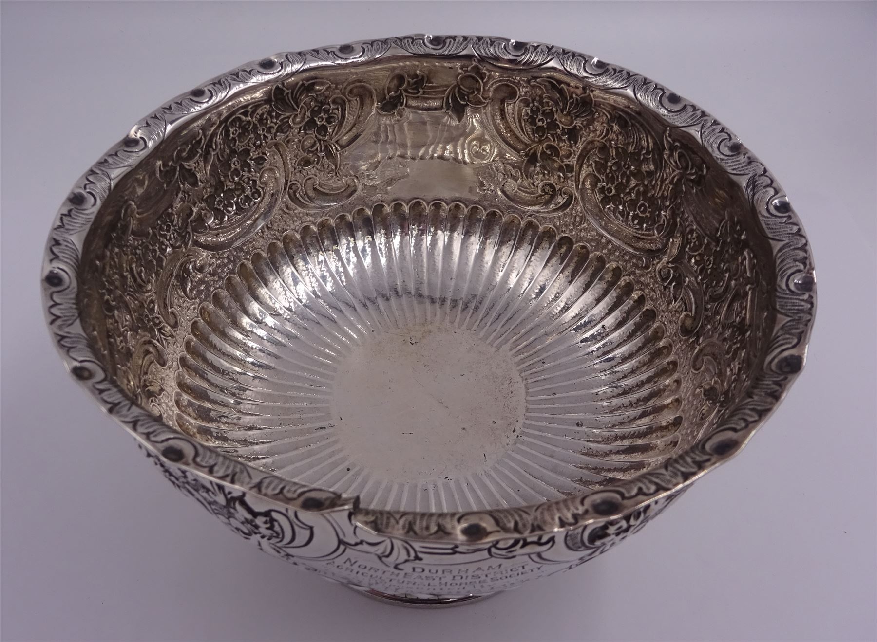 Late Victorian silver rose bowl, of circular form with embossed foliate and C scroll decoration, and engraved personal dedication, upon a part fluted spreading circular foot, hallmarked Wakely & Wheeler, London 1898, H11.5cm D18cm, approximate weight 11.67 ozt (363.2 grams)