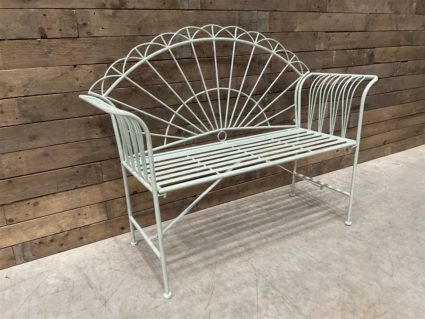 Wrought metal two seat garden bench, sunburst back, painted in pale green finish