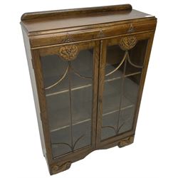 Early 20th century oak bookcase or display cabinet, raised back over two astragal glazed doors with carved decoration, enclosing two shelves