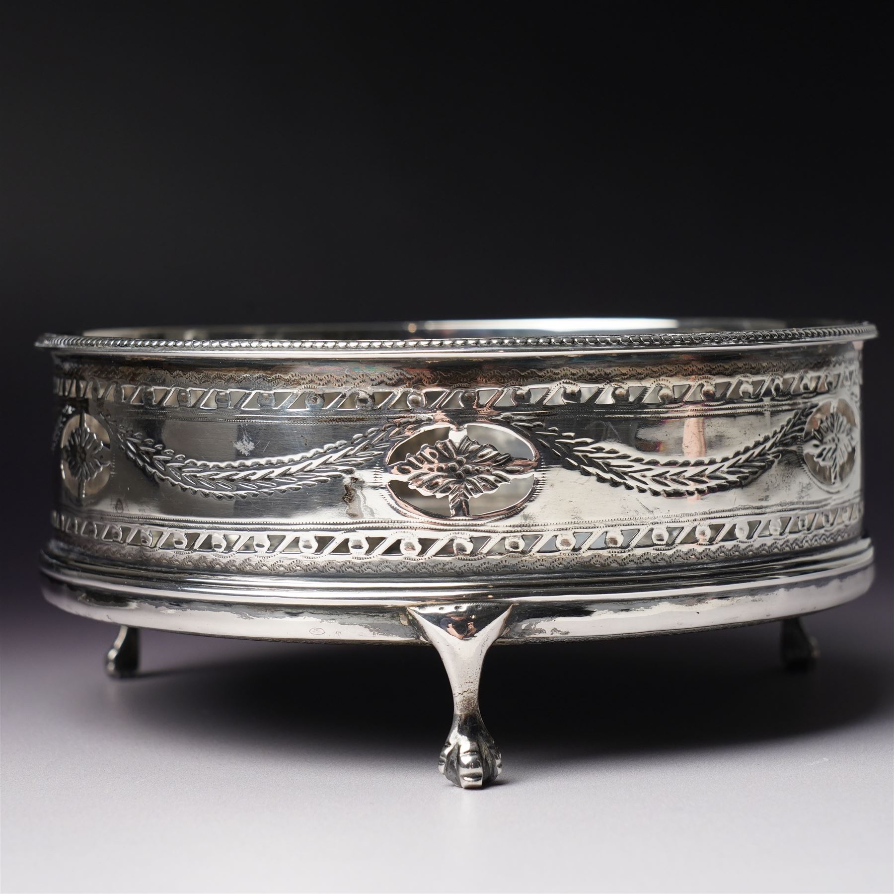George III silver circular stand, originally a cruet stand, with pieced rim decorated with garlands and swags with turned wood base on claw and ball feet D14cm