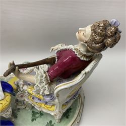 20th century Naples figure group, modelled as a seated female figure playing the lute seated, before a male figure stood holding a sheet of music, each in period dress, upon an oval base with gilt heightened scroll edge, with crowned N mark beneath, H31.5cm L33cm
