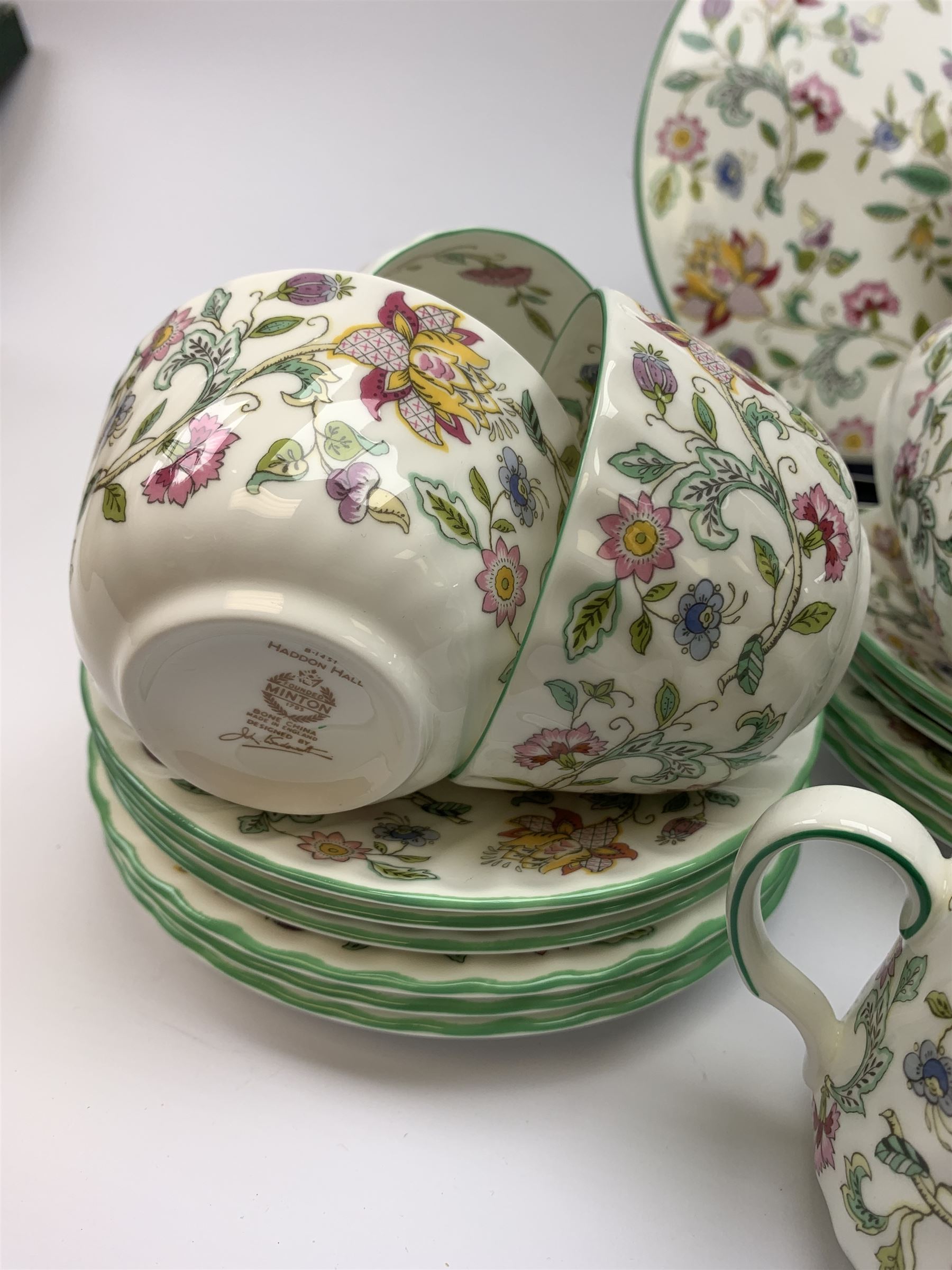Minton Haddon Hall pattern tea wares, comprising stand, sandwich plate, oval serving dish, knife, eleven tea cups, six saucers, and three further smaller saucers, six side plates, open sucrier, and milk jug. 