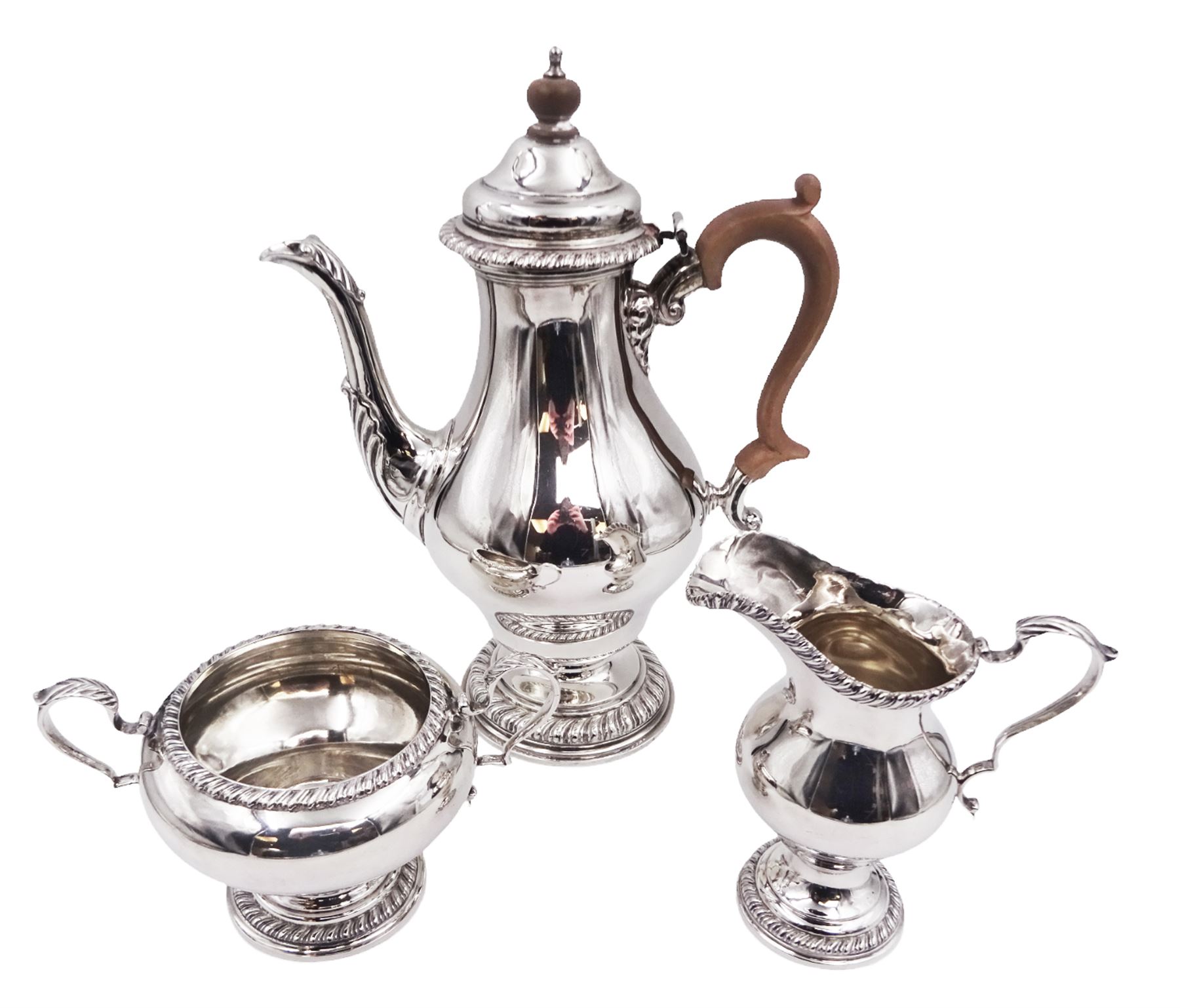 Mid 20th century three piece silver coffee service, comprising coffee pot, milk jug and twin handled open sucrier, of waisted form upon circular domed foot,  with oblique gadrooned rim, the milk jug and sucrier with acanthus capped handles, the coffee pot with wooden handle and finial, hallmarked William Comyns & Sons Ltd , London 1961, coffee pot H27.5cm