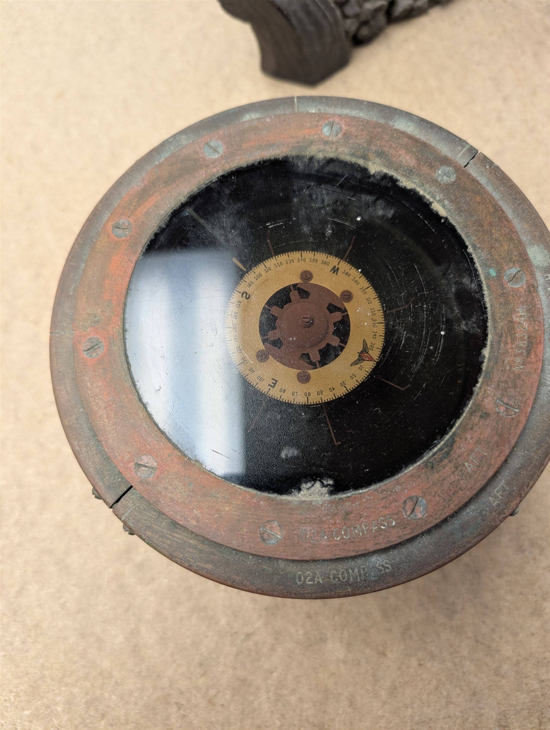 Military issue 02A gimbal compass, with broad arrow mark, together with a brass porthole and a piece of wood carved with portrait and foliage