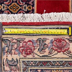North West Persian Senneh hand-knotted runner, field with a central stepped medallion design in madder red and cream, in a series of linked lozenges filled with finely composed floral sprays and stylized roses, surrounded by densely patterned repeating geometric motifs, enclosed within a narrow main border with floral meander, flanked by multiple guard stripes, with fringe ends 