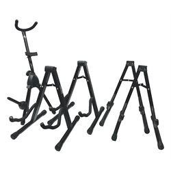 Four folding tubular guitar stands, two by RockJam; and folding tubular saxophone stand (5)