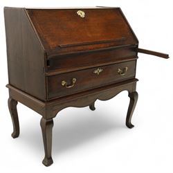 Early 18th century George I oak bureau on original stand, the fall front enclosing an arrangement of correspondence drawers and pigeonholes over central well, fitted with single long drawer below, the shaped apron over cabriole supports with pad feet