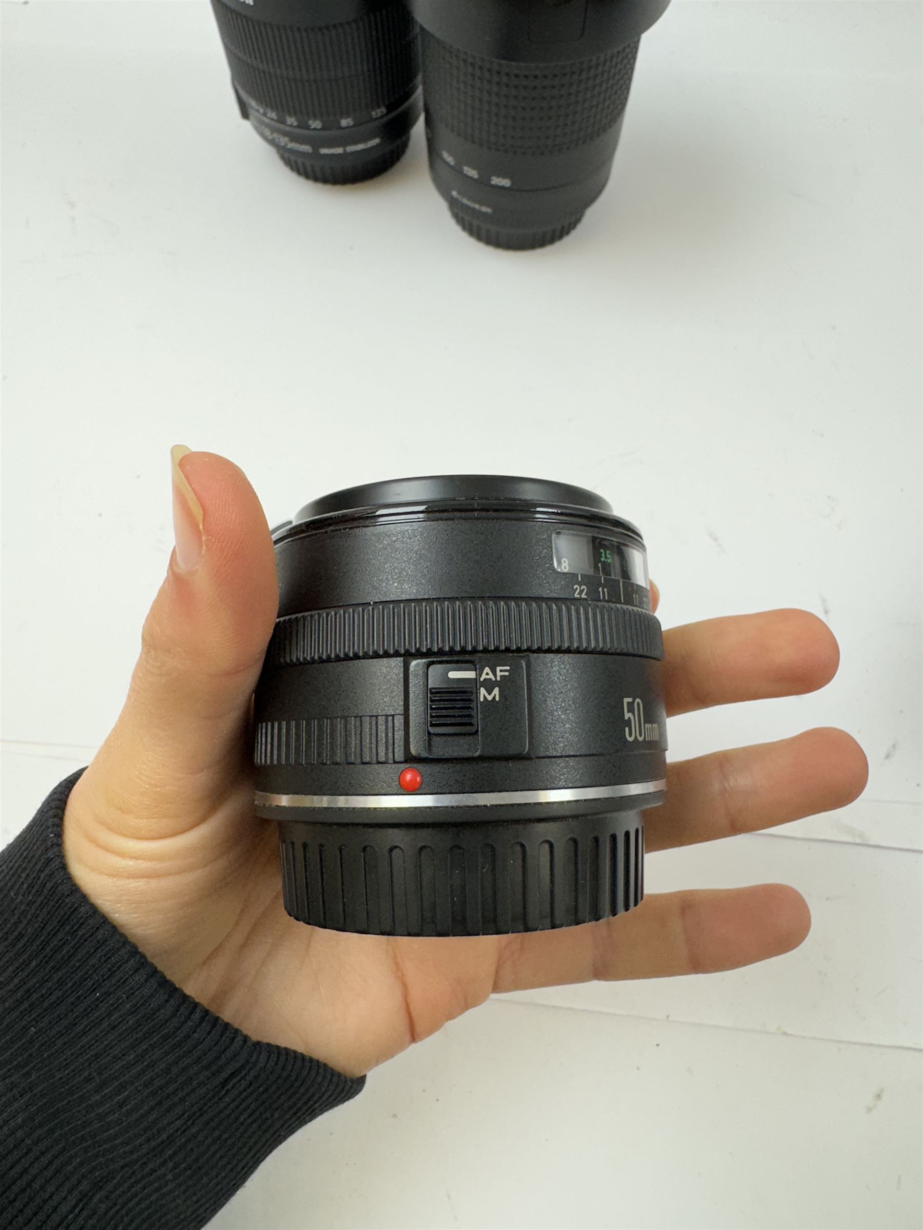 Three Canon EF camera lenses, comprising 100-300mm 1:5.6 lens serial no. 1057918, 50mm 1-1.8 lens serial no. 1153183 and a 55-200mm 1:4.5-5.6 USM zoom lens serial no. 2100282B, together with a Canon EF-S 18-135mm 1:3.5-5.6 image stabiliser lens serial no. 7242517341