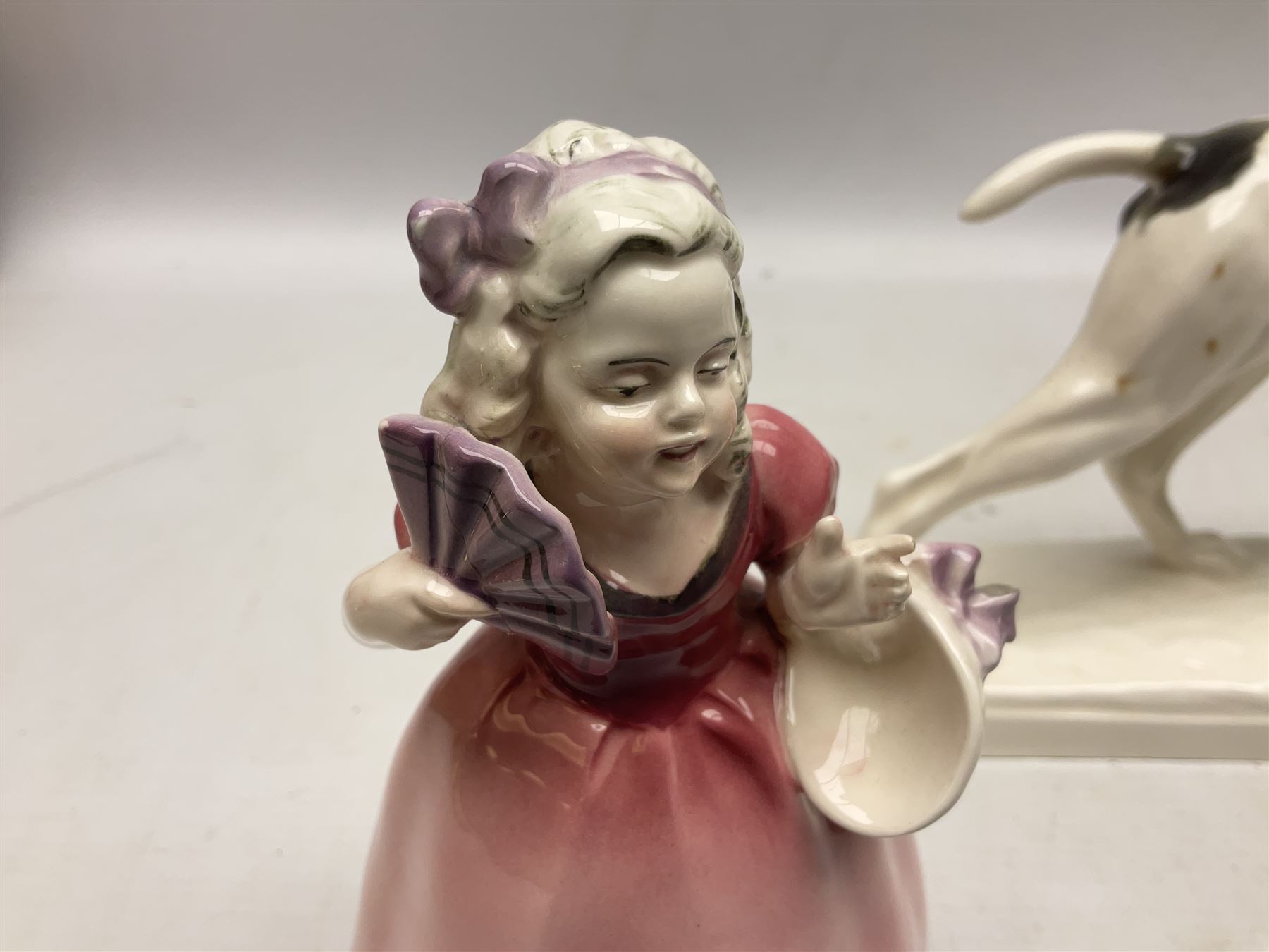 Early 20th century Katzhütte figure of a pointer dog, and figure of a young girl holding basket and fan, both with green cat H house printed mark beneath, dog L25cm