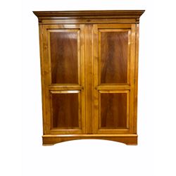 Large figured mahogany and cherry wood double wardrobe, the projecting cornice over figured panelled doors, fitted with hanging rails and shelves, skirted base