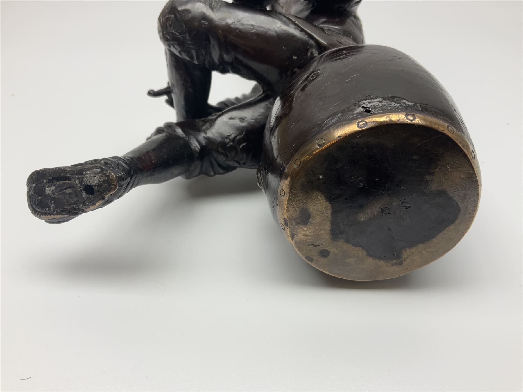 Oriental bronze figure of a gentleman, modelled seated upon barrel with a pipe in one hand and a flask in the other, H21cm