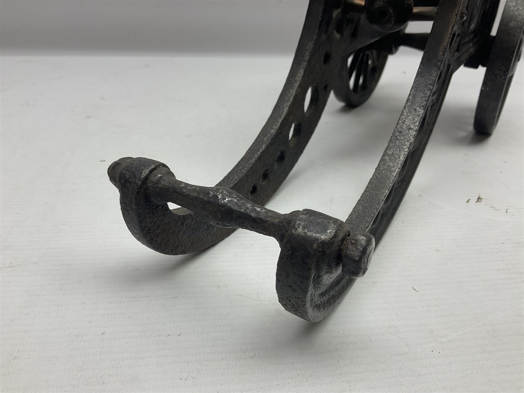 Victorian cast-iron and steel signal cannon, approximately half-inch bore, with 23cm ringed barrel and cylindrical trunnions, on a cast iron carriage with two twelve-spoked wheels and guilloche pierced swept back support, L43cm overall