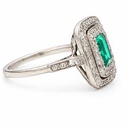 Early 20th century palladium emerald and diamond halo cluster ring, single rectangular cut emerald of approx 0.30 carat, surrounded by two rows of milgrain set diamonds and diamond set shoulders