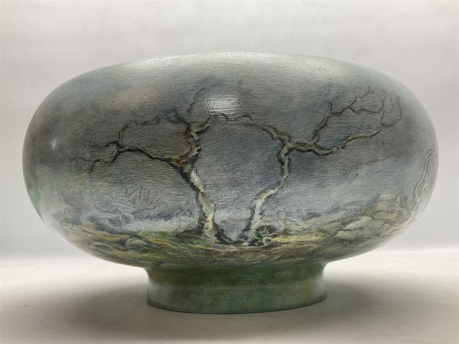 Wooden hand painted bowl, decorated with trees on a blue ground, signed Phil Crennell beneath, D28cm