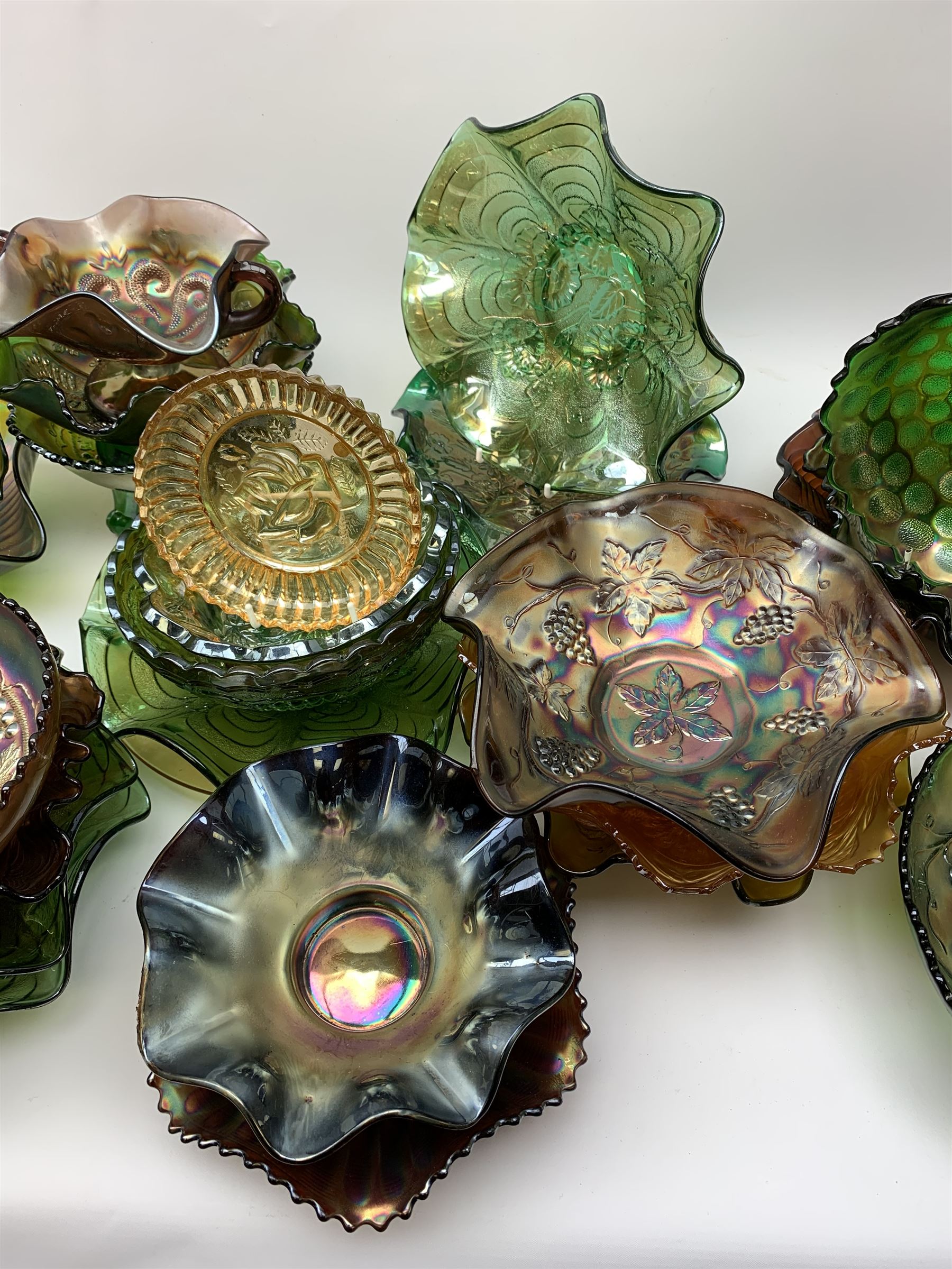 A collection of Carnival glass, to include marigold, green, and amethyst, bowls, dishes, and comports, various patterns including fruiting vines, peacocks, and an example decorated with a Horseshoe and detailed Good Luck. 
