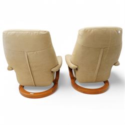 Himolla - A pair of swivel reclining chairs, beige upholstered with padded arms and high back rest, raised on a laminated circular wooden base with swivel mechanism 