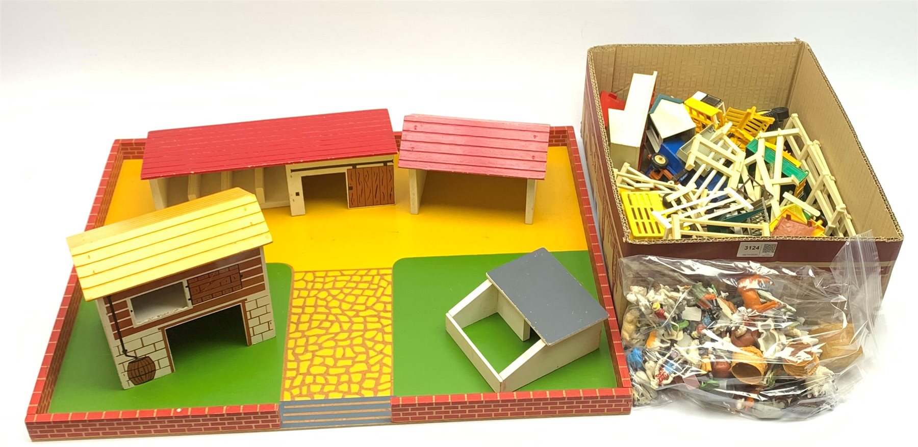 Farmyard layout including large walled wooden base board 61 x 45cm with various wooden buildings and plastic accessories, die-cast tractors and farm machinery by Britains, Ertl etc, plastic farm animals and figures by Britains etc