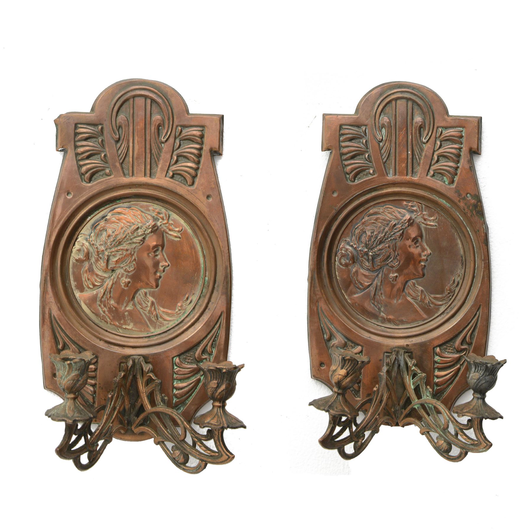 Pair of late 19th/early 20th century Art Nouveau copper twin branch wall sconces, each with shaped back plate chased with a central panel of a maiden in profile above and surmounted by foliate motifs, supporting two foliate open cast branches with bud sockets above conforming drip pans, H31cm W16cm D8.5cm
