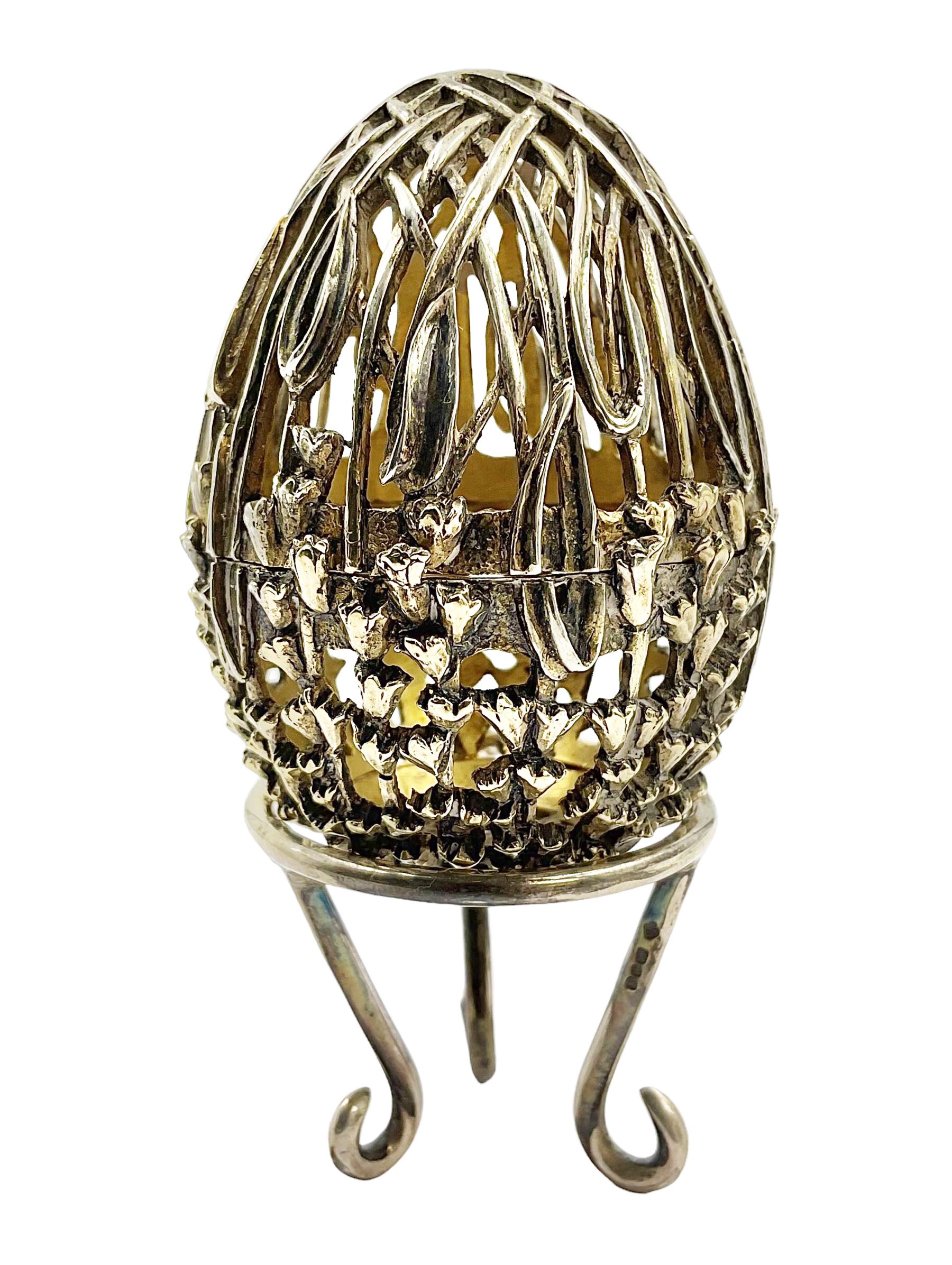 Modern silver limited edition Easter egg, no. 70/500, the gilt openwork body decorated with cascading bluebells and hinged cover with pierced circular panel set with a single faceted purple stone, opening to reveal a gilt interior, upon silver stand with three scrolling pad feet, each hallmarked St James House Company, London 1981, height including stand 8cm
