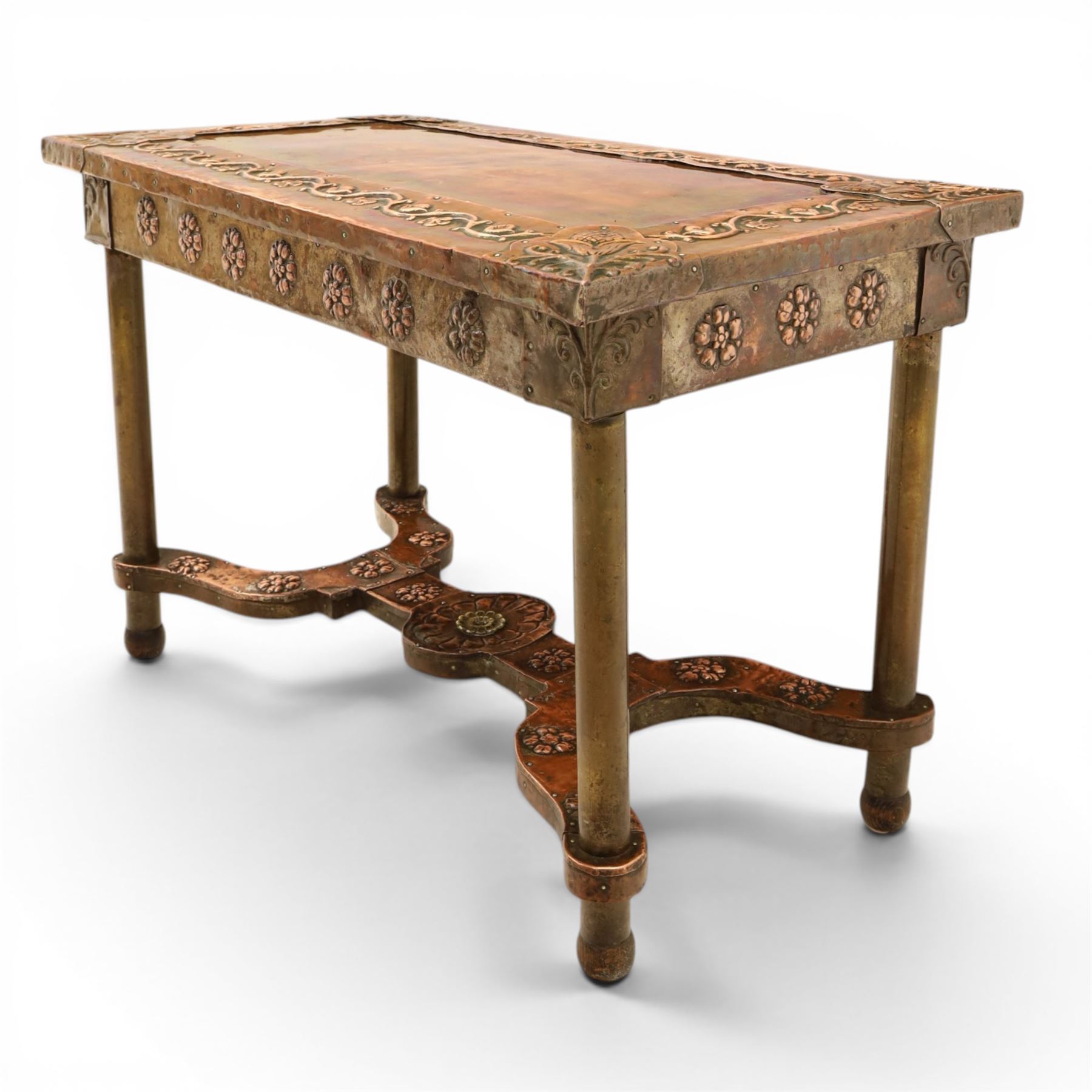 Arts and Crafts copper mounted coffee table, rectangular top with embossed foliate border and stylised corner motifs, studwork detail, on cylindrical supports united by pierced shaped stretcher with applied flowerhead bosses