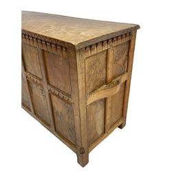 Gnomeman - oak blanket box, all-over adzing, the hinged top over figured and burr panelled front, decorated with carved crenellations and arcade, carved with gnome signature, pierced handles to each end forming the central rail, wrought metal hinges, on stile supports, by Tom Whittaker, Littlebeck, Whitby