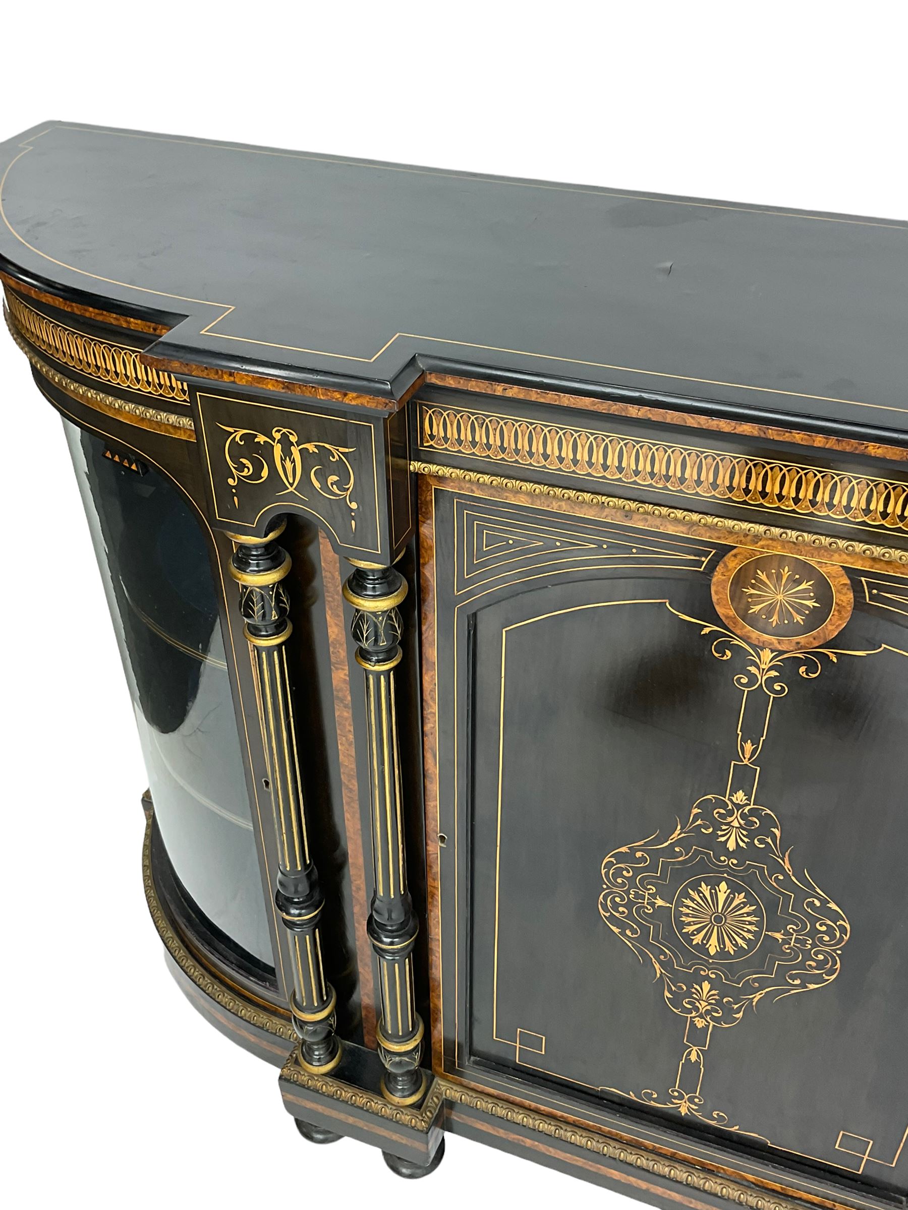Victorian ebonised and inlaid credenza, break-front with curved ends, the front fitted with two curved glazed doors and central panelled door, inlaid with scrolling foliate and star motifs, quadruple turned and fluted pilasters to front, gilt egg and dart moulded edge on plinth base with figured walnut band, on turned feet