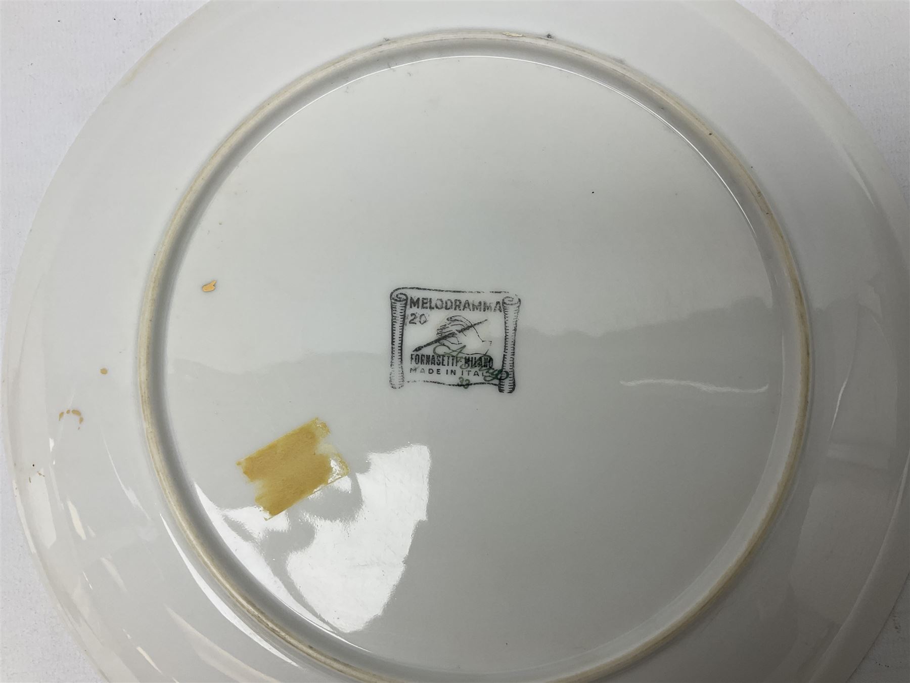 Three Fornasetti plates from the Melodramma series, each depicting a operatic portraits within a border of operatic emblems on gilt ground, with printed mark beneath, D25cm 