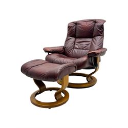 Ekornes Stressless, swivel armchair upholstered in red leather, with matching footstool supported on Oak bases