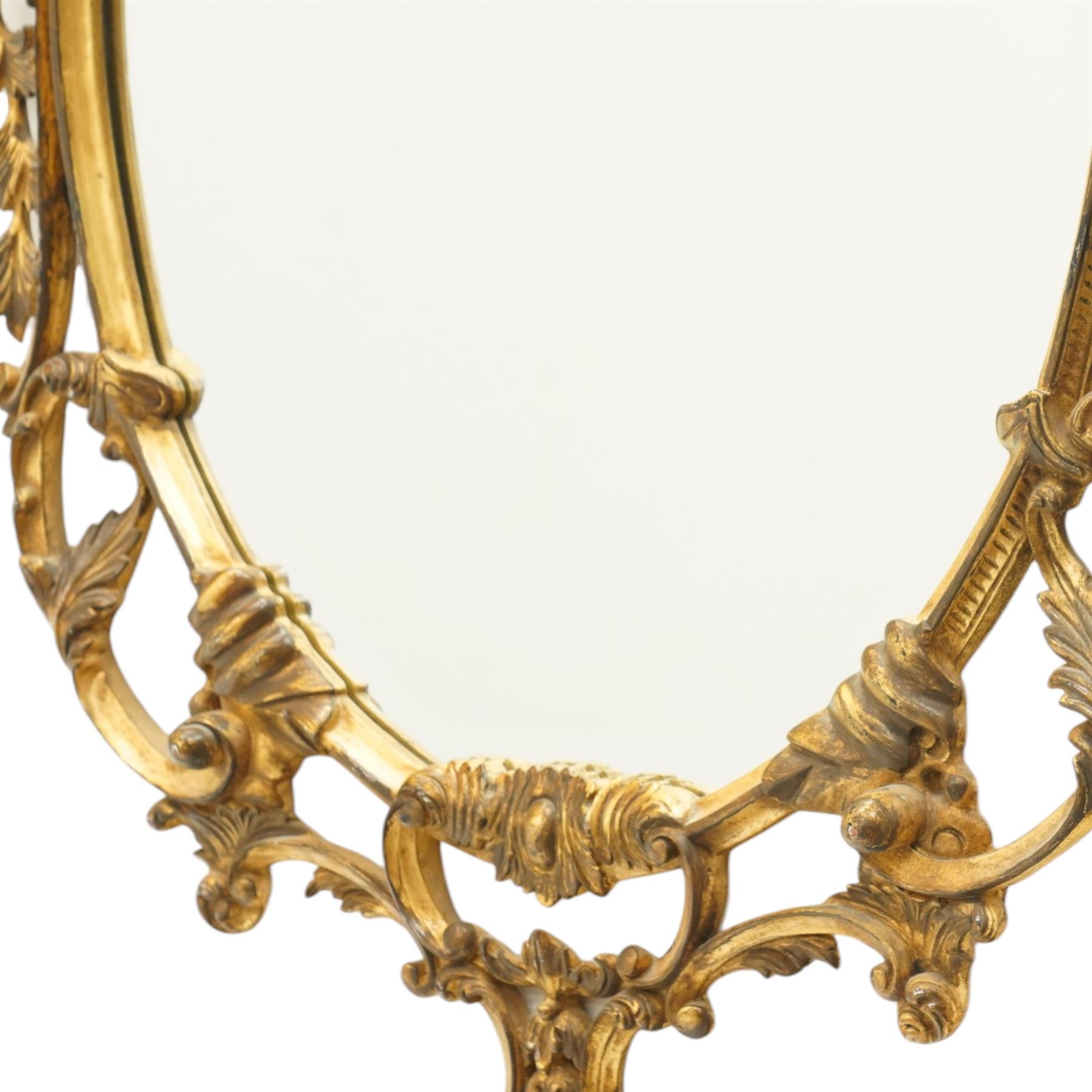 Rococo design giltwood and gesso wall mirror, oval plate within moulded frame, pierced cresting and apron, decorated with acanthus leaves, flowerheads and trailing foliage