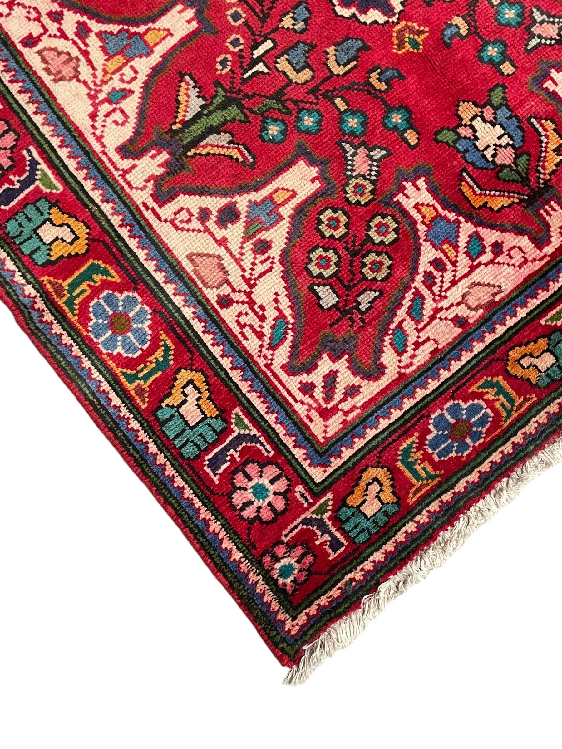 Persian Azerbaijan crimson ground rug, the field decorated with central floral motif and surrounded by trailing floral branches, enclosed within a shaped outer band with further floral decoration, the border with repeating flower heads, geometric guard stripes 