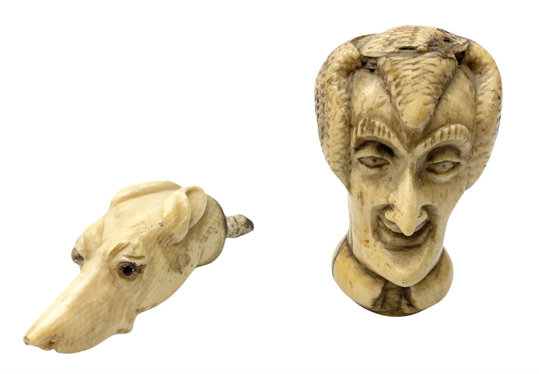 19th century carved ivory walking cane handle, modelled as the head of a greyhound with inset glass eyes, together with a further 19th century ivory example, modelled as a caricature of a gentleman's head, (2)