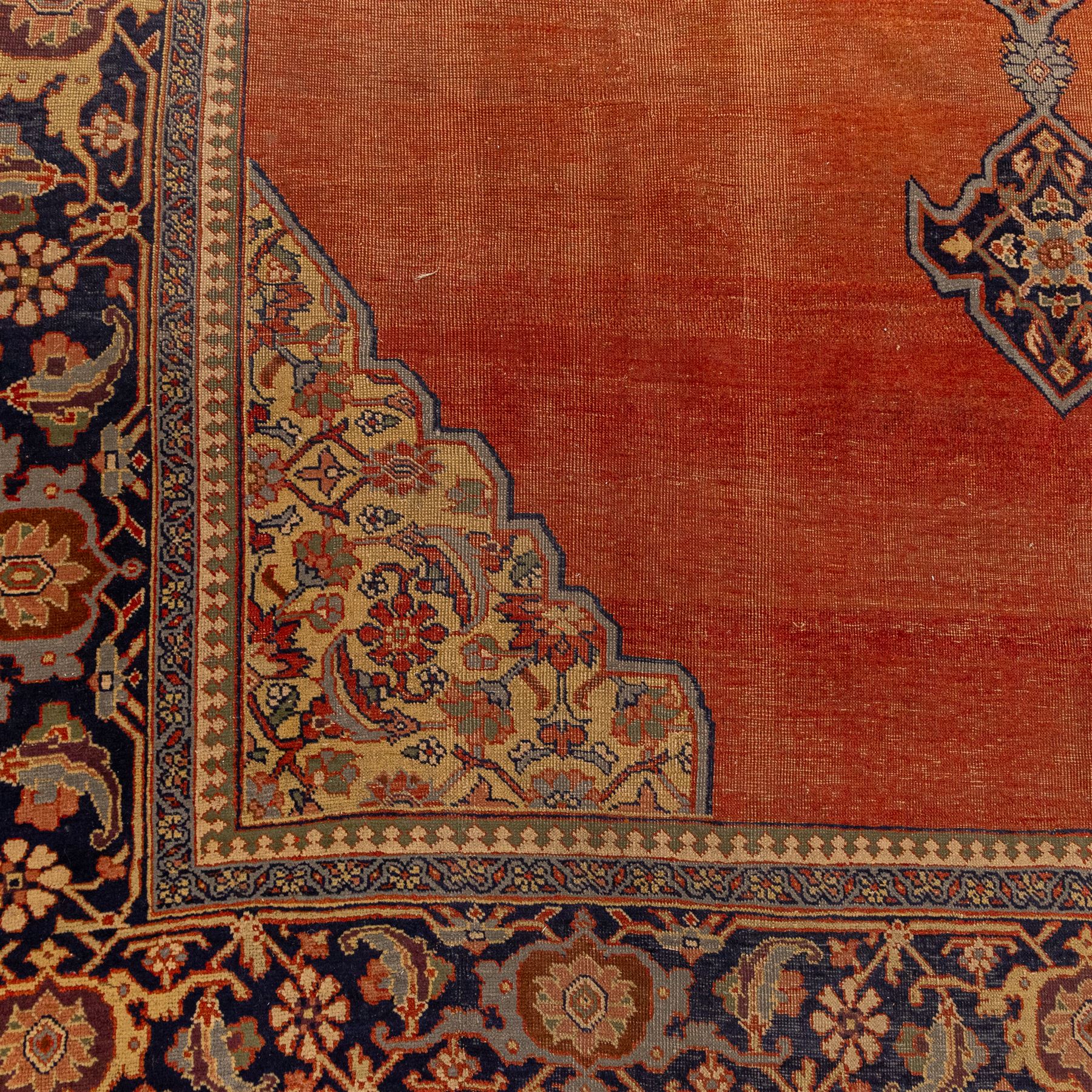 North West Persian Tabriz hand-knotted carpet, salmon field with central elongated lozenge medallion intricately filled with scrolling arabesques and palmettes, framed by stylized corner spandrels within a broad indigo main border  of bold palmettes and floral vinery between multiple guard stripes, rendered in tones of terracotta, sage green, and soft ivory, with cotton fringe ends 