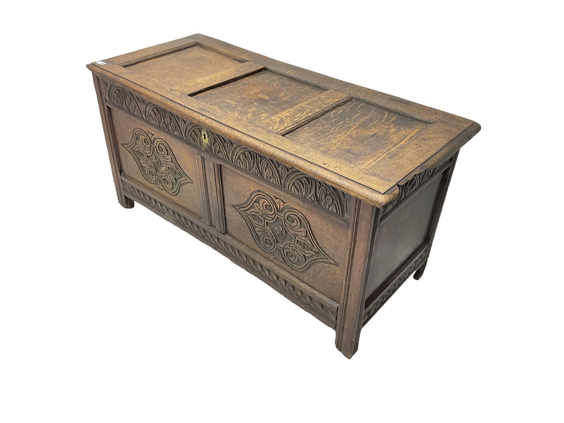 18th century oak blanket chest or coffer, rectangular hinged top with three panels and moulded edge, frieze carved with lunette and acanthus leaf decoration, two front panels carved with scrolling motif, raised on stile supports