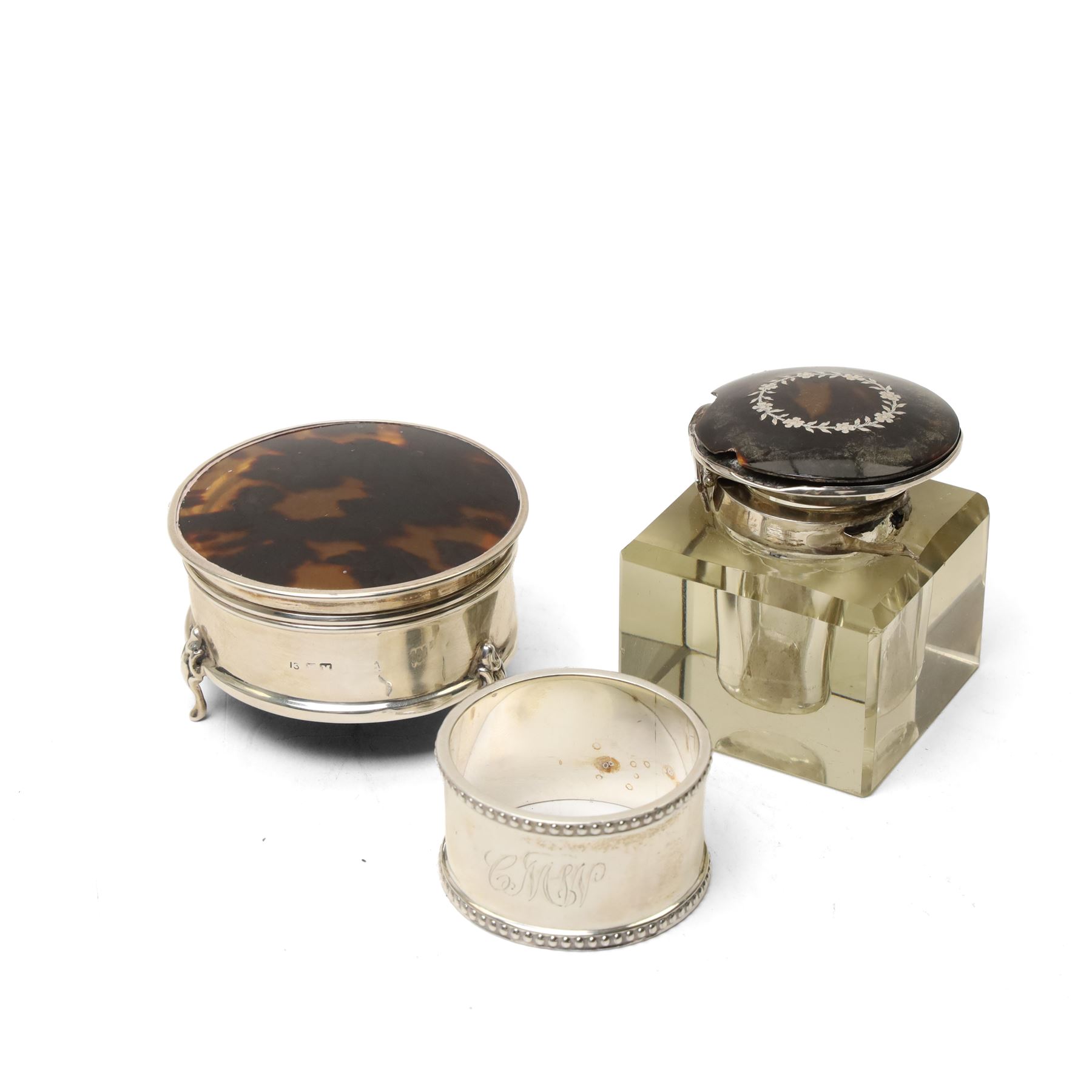 Silver circular ring box with hinged tortoiseshell cover, glass block inkwell with pique tortoiseshell cover Birmingham 1921 and a silver napkin ring (3)