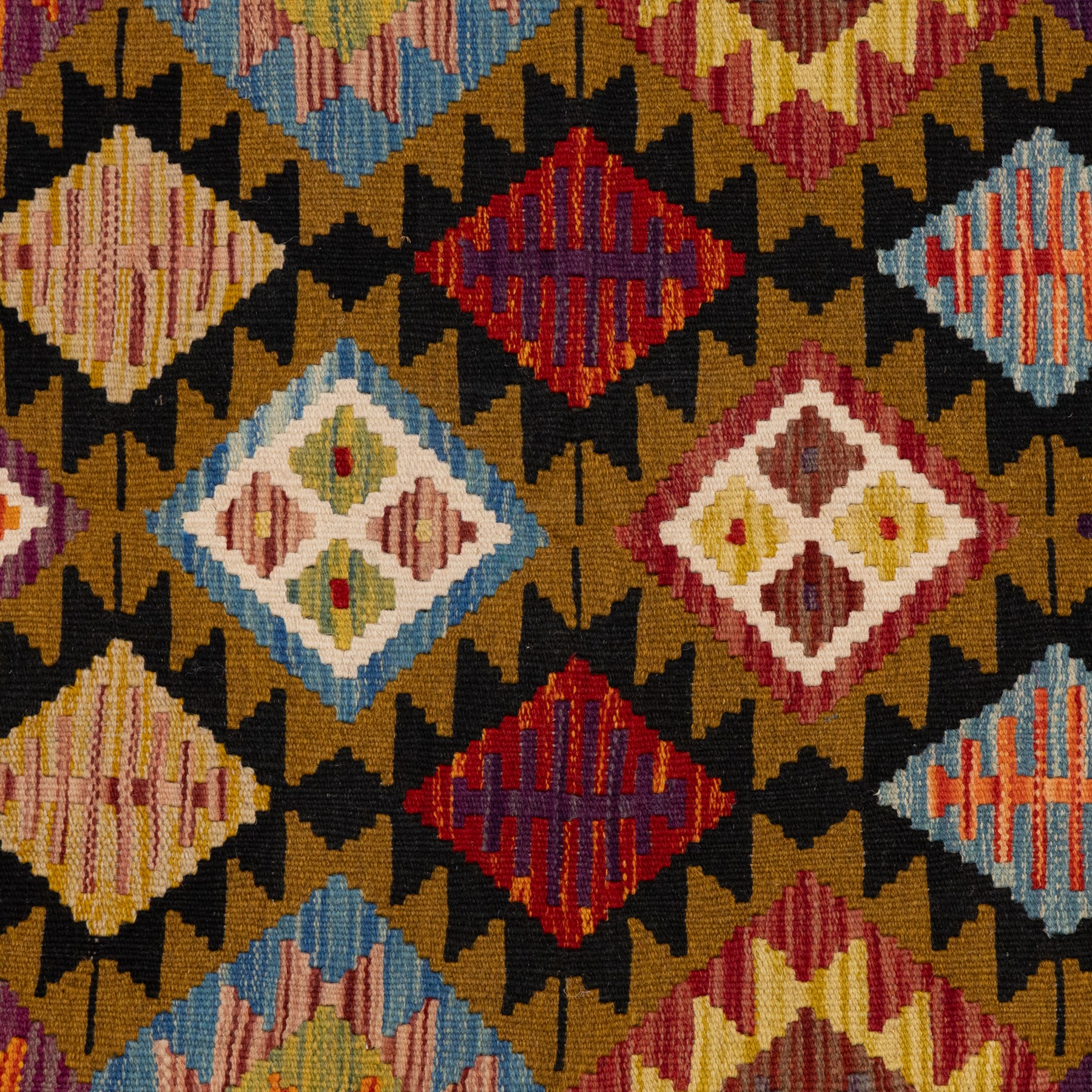 Afghan kilim rug, the field in earthy tones decorated with columns of repeating lozenges with further geometric motifs, the teal guard band with repeating stepped lozenges heightened with ivory