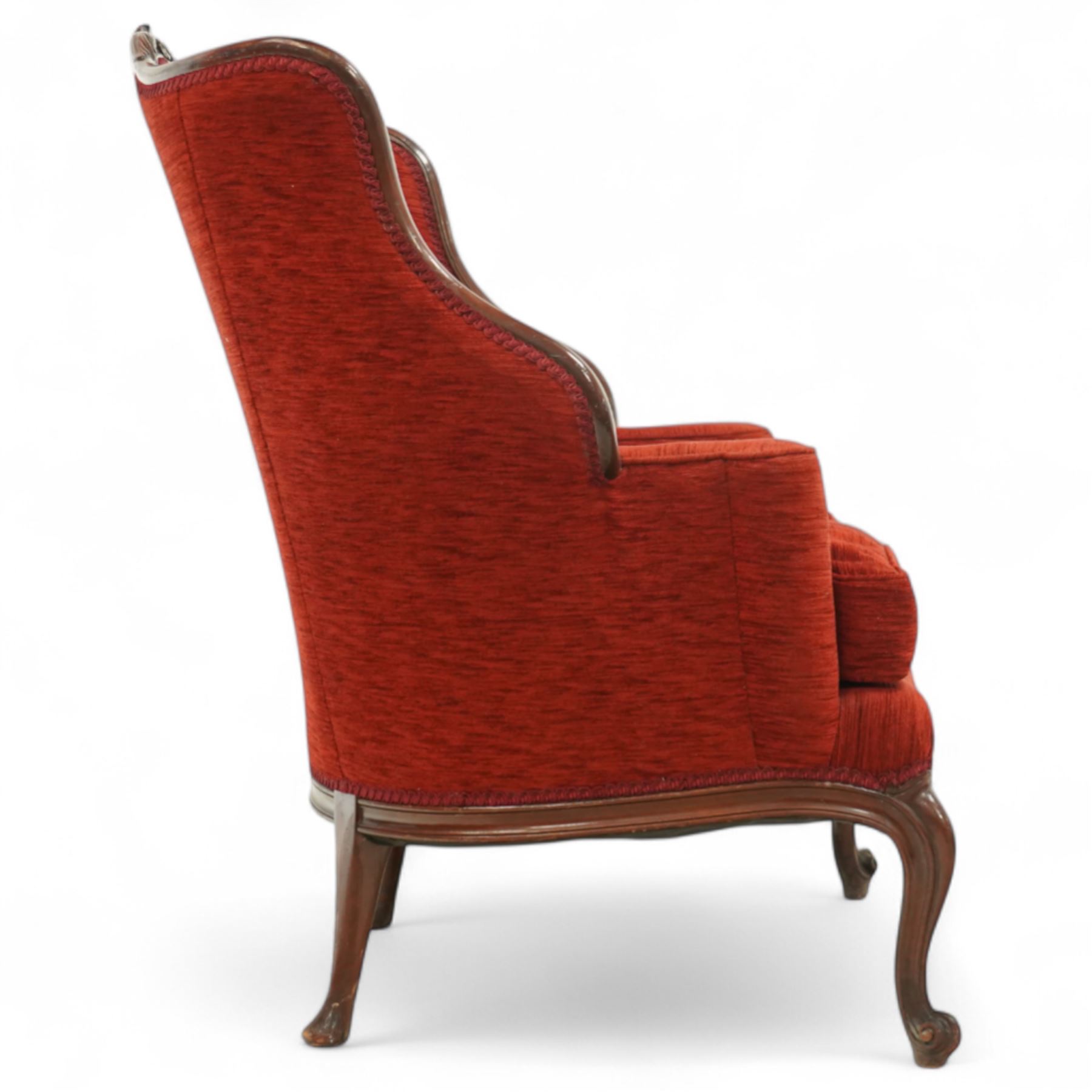 19th century Rococo revival upholstered armchair, red textured fabric over a carved walnut frame, shaped back and sides, floral carved serpentine seat rail, on cabriole supports 